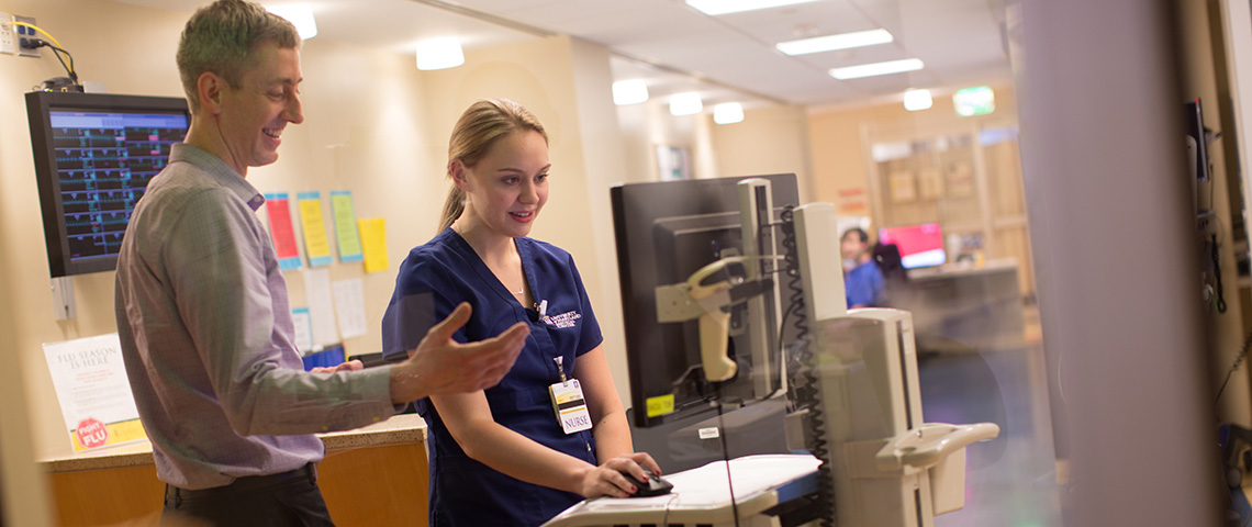 Nurse working on a computer with senior member guiding her